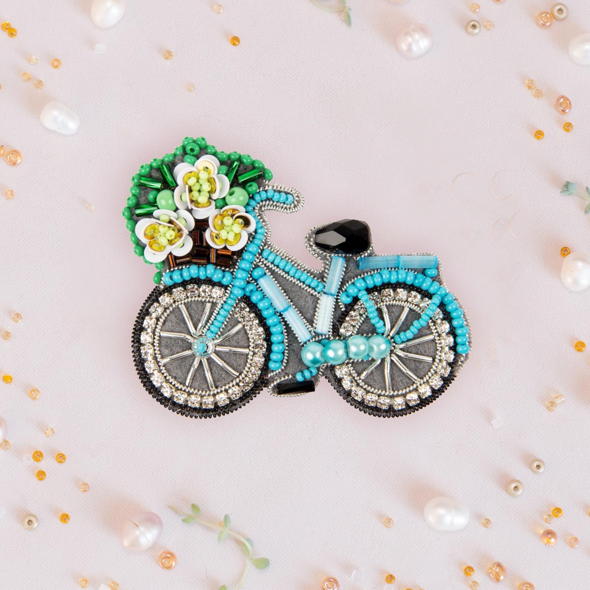 a brooch with a bicycle and flowers on it
